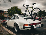 White Porsche 911 SC with Bicycle Mounted on Top
