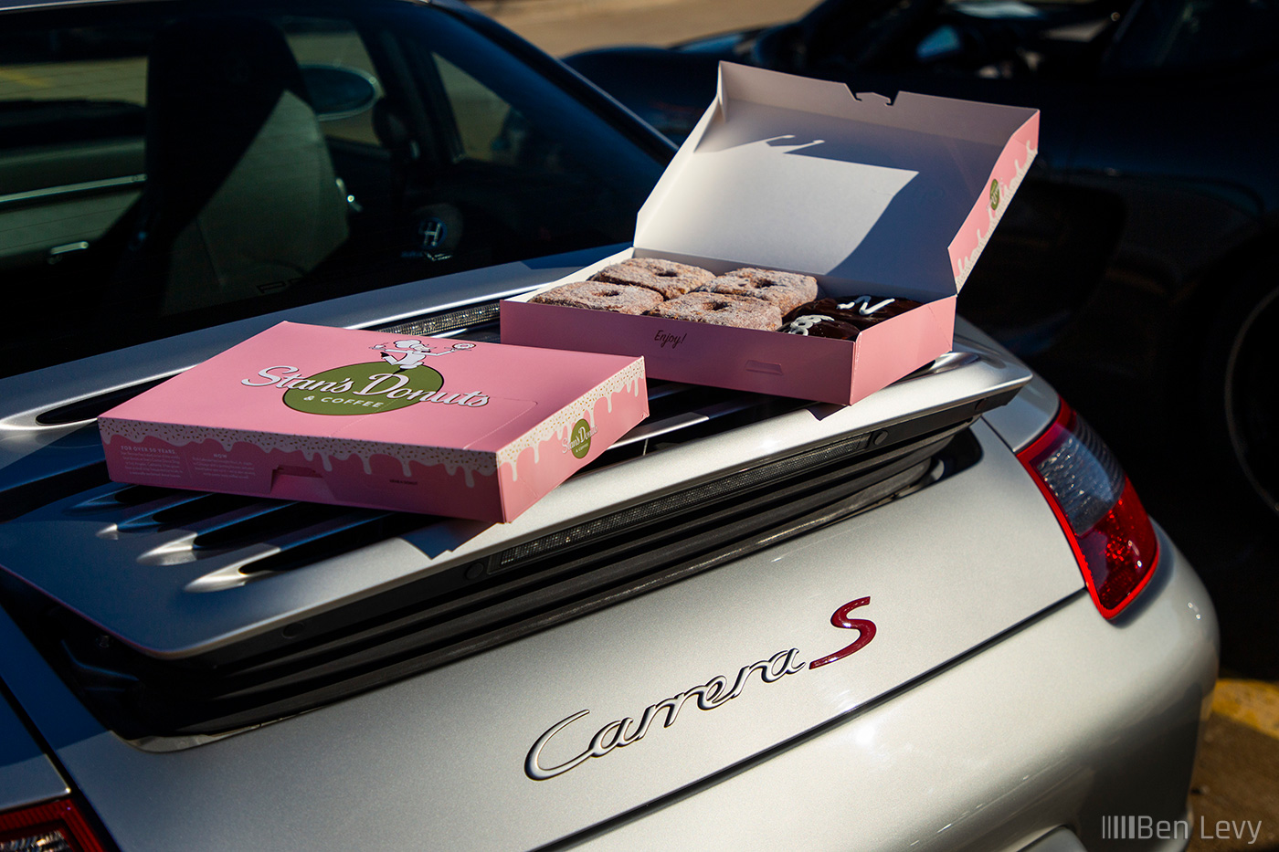 Boxes of Stan's Donuts on the Wing of a Porsche Carrera S