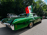 Green Two-Door Chevrolet Caprice with Mexican Flag Waving