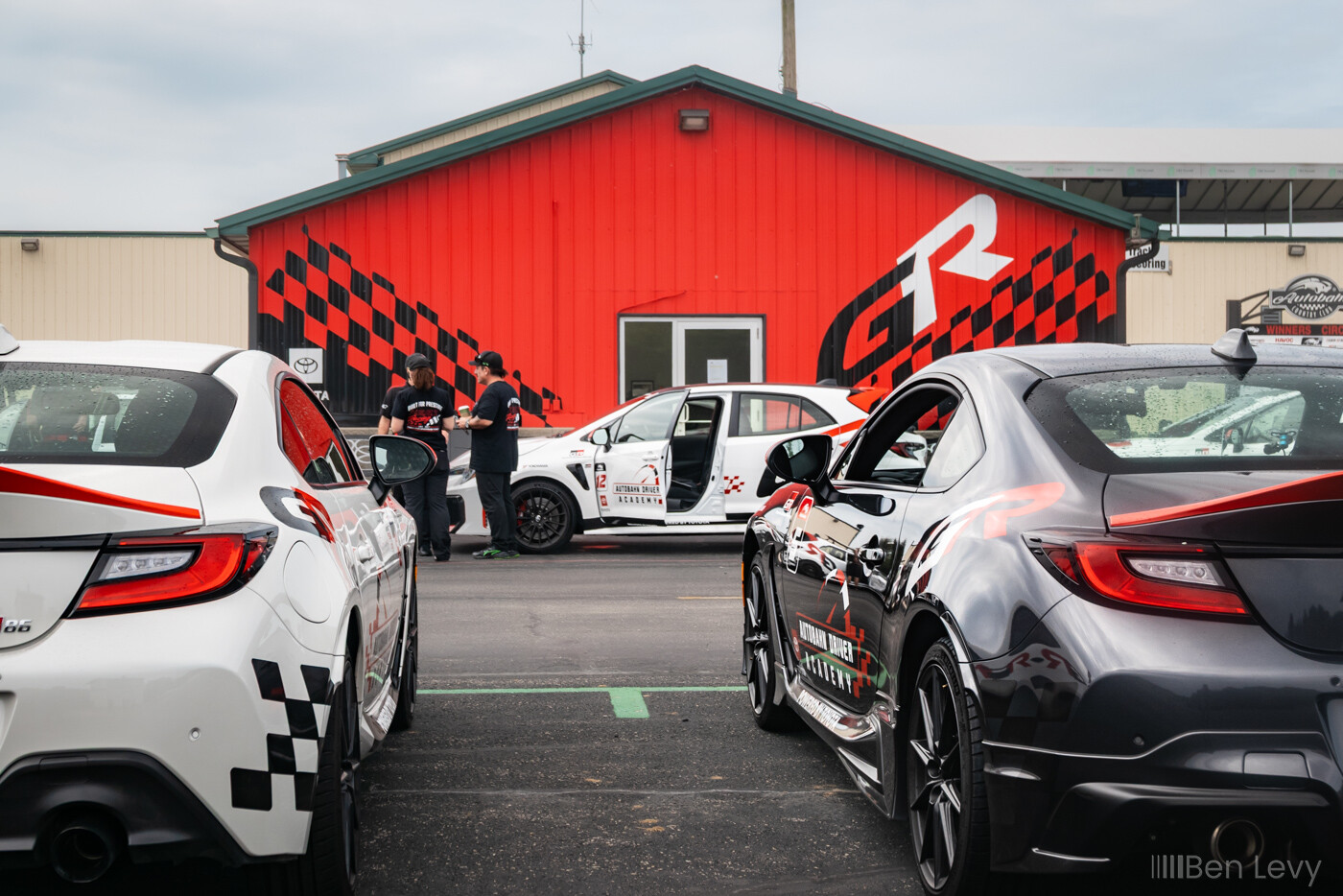 Tail Lights of two Toyotas in front of a Building with a Gazoo Racing Theme