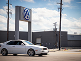 White Volkswagen Corrado by VW Dealership Sign