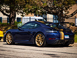 Blue Porsche 718 Cayman GT4 with Gold Stripe