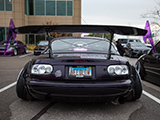 Purple Miata with clear taillights and huge wing