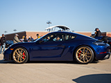 Blue Porsche Cayman GT4 on gold wheels