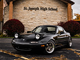 Black Mazda Miata with Hardtop in front of St. Joseph High School